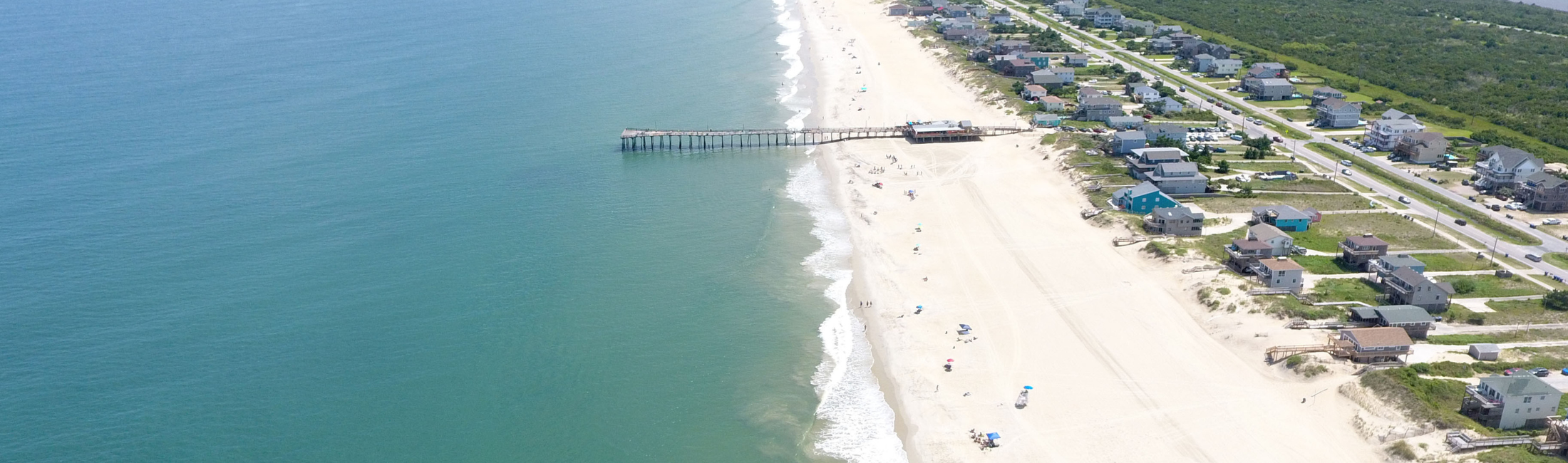 Aerial photo of pier over a large white sand beach in south Nags Head, NC.  